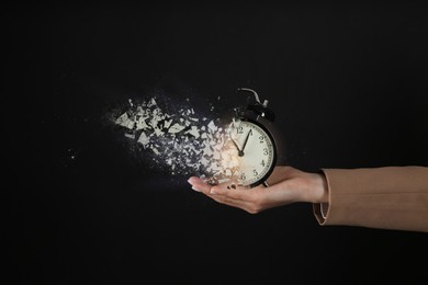 Image of Businesswoman holding dissolving alarm clock on black background, closeup. Time is running out