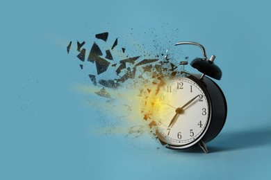 Image of Black alarm clock shattering into pieces on light blue background. Flow of time