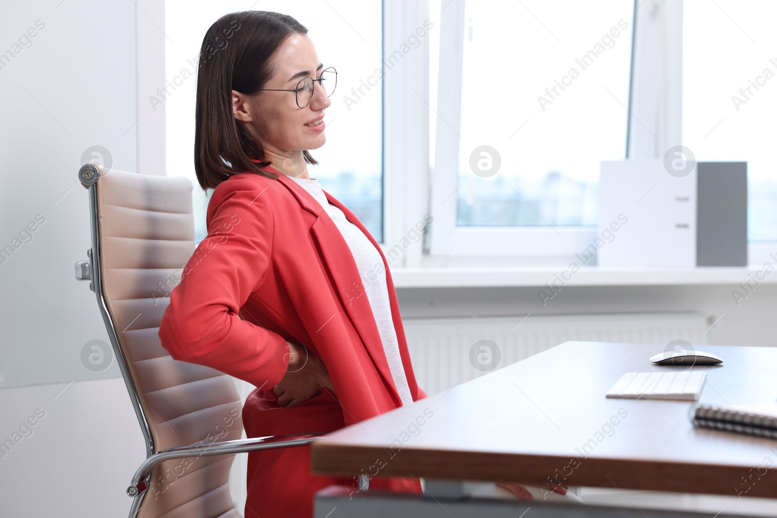 Photo of Woman suffering from back pain in office. Symptom of poor posture