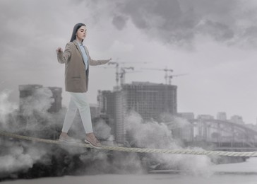 Image of Concentrated businesswoman walking rope over city. Concept of risk and balance