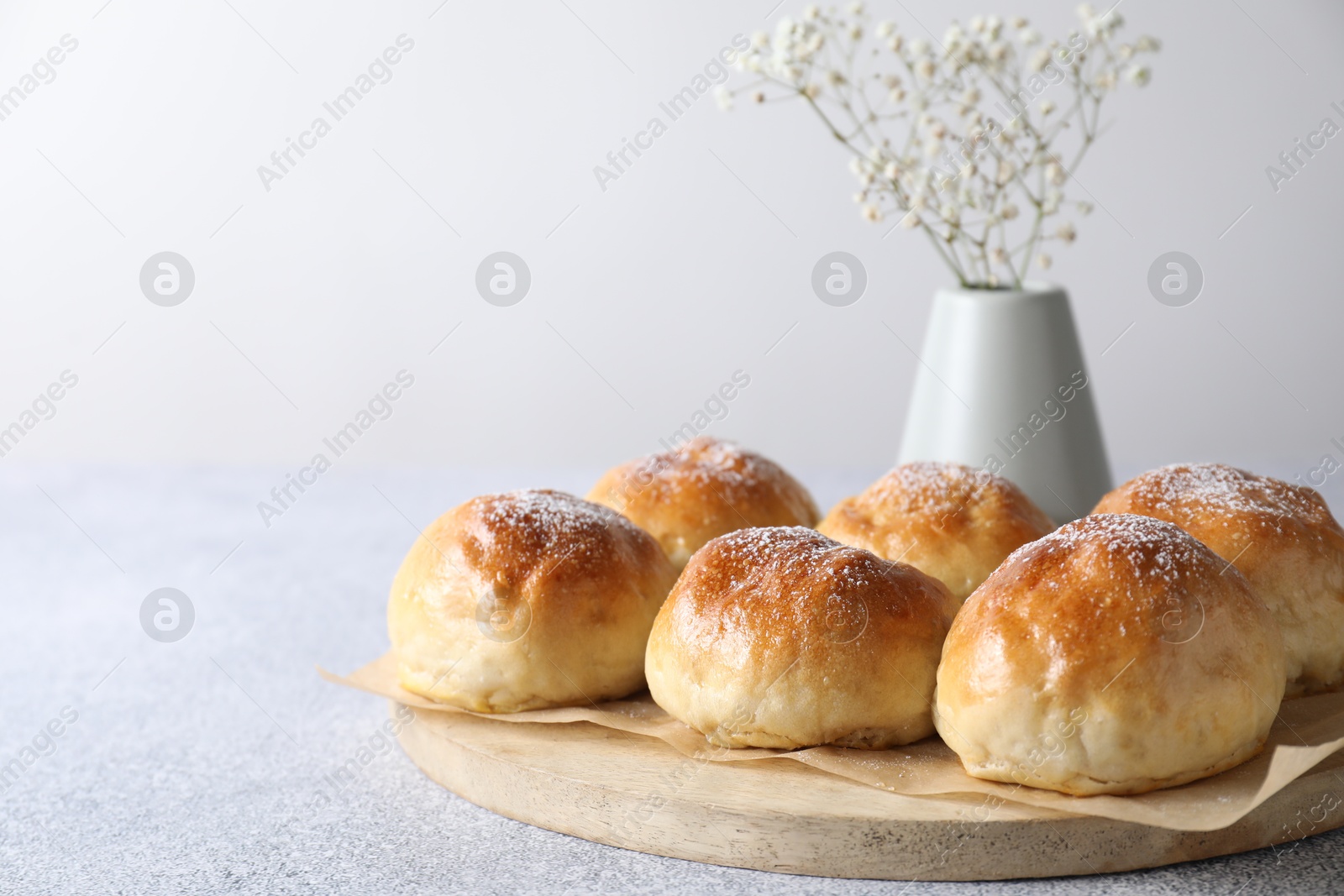 Photo of Delicious dough balls and flowers on grey table, closeup. Space for text