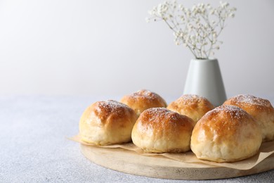 Delicious dough balls and flowers on grey table, closeup. Space for text