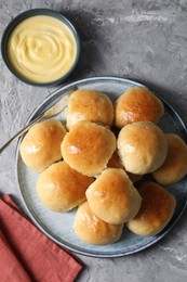 Photo of Delicious dough balls and sauce on grey table, top view