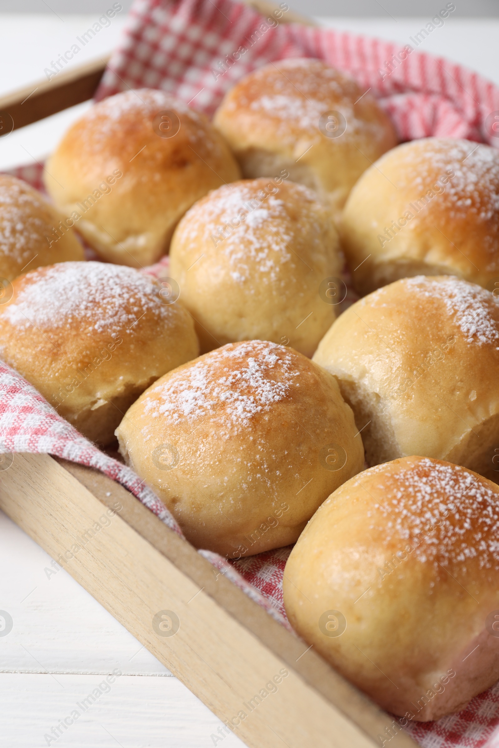 Photo of Delicious dough balls in crate on white table, closeup