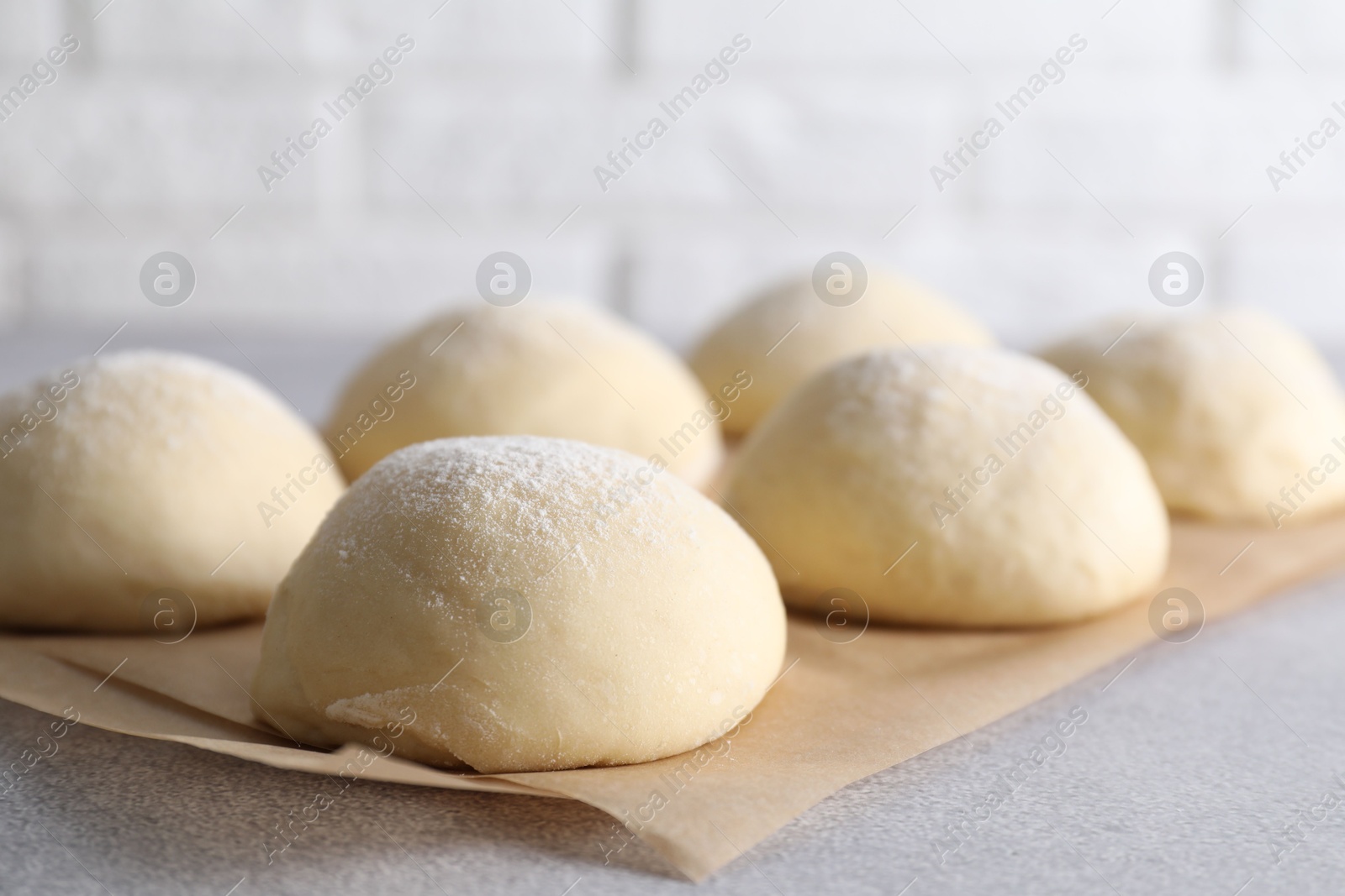 Photo of Raw dough balls on light grey table, closeup