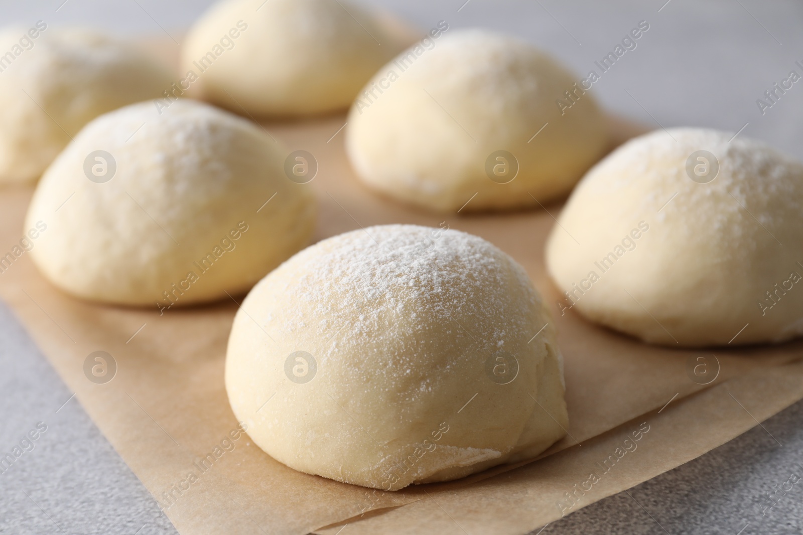 Photo of Raw dough balls on light grey table, closeup