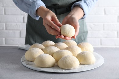 Woman making dough ball at grey table, closeup