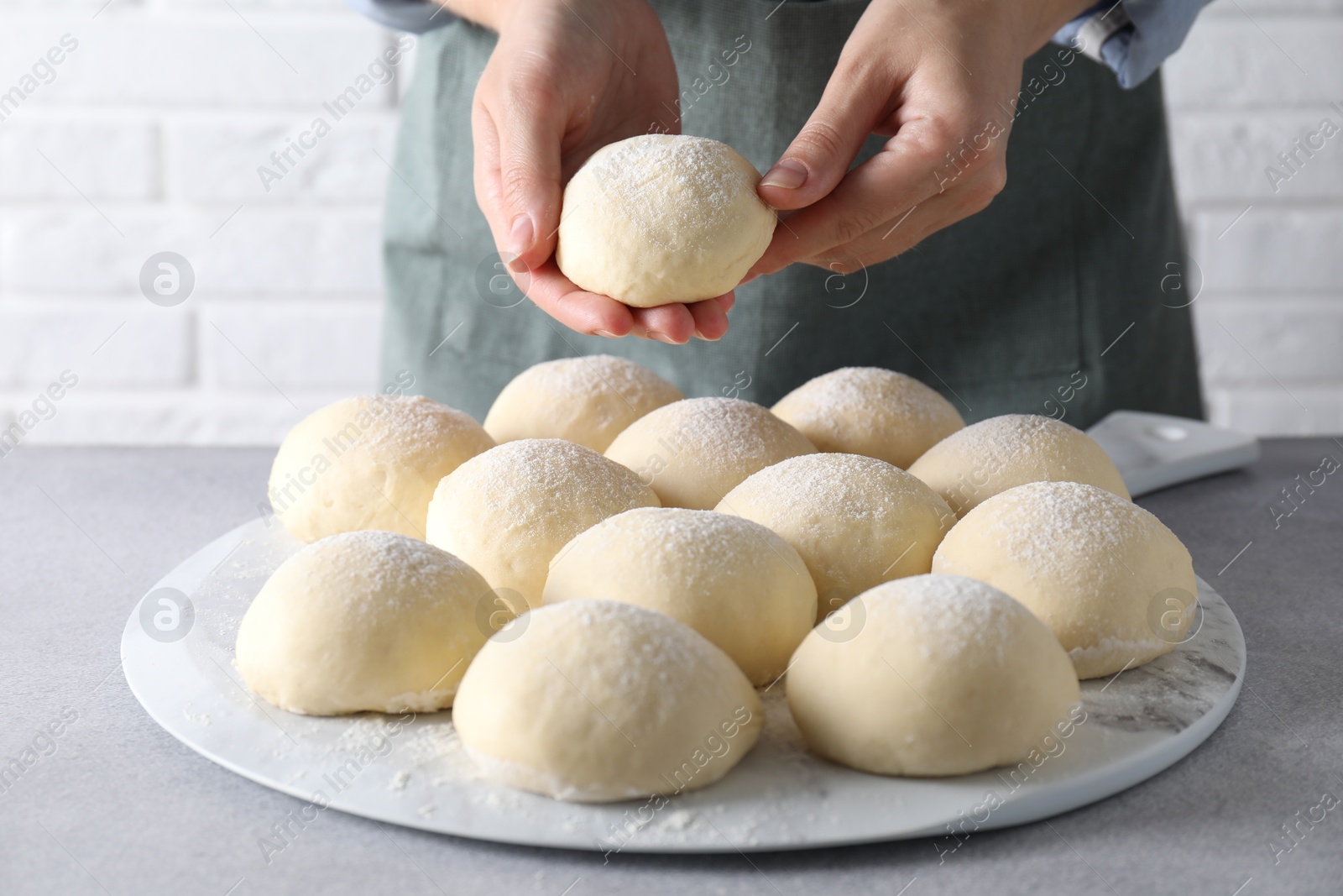 Photo of Woman making dough ball at grey table, closeup