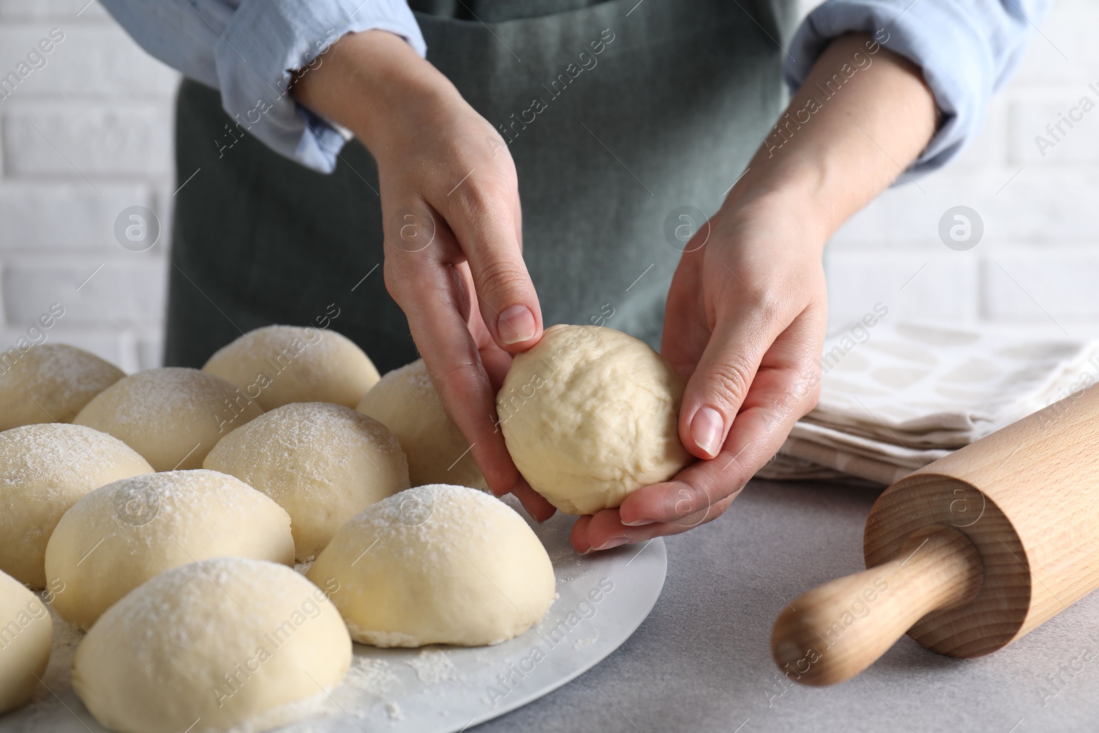 Photo of Woman making dough ball at grey table, closeup