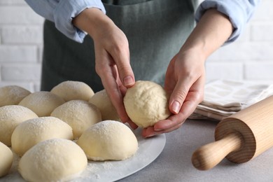 Woman making dough ball at grey table, closeup