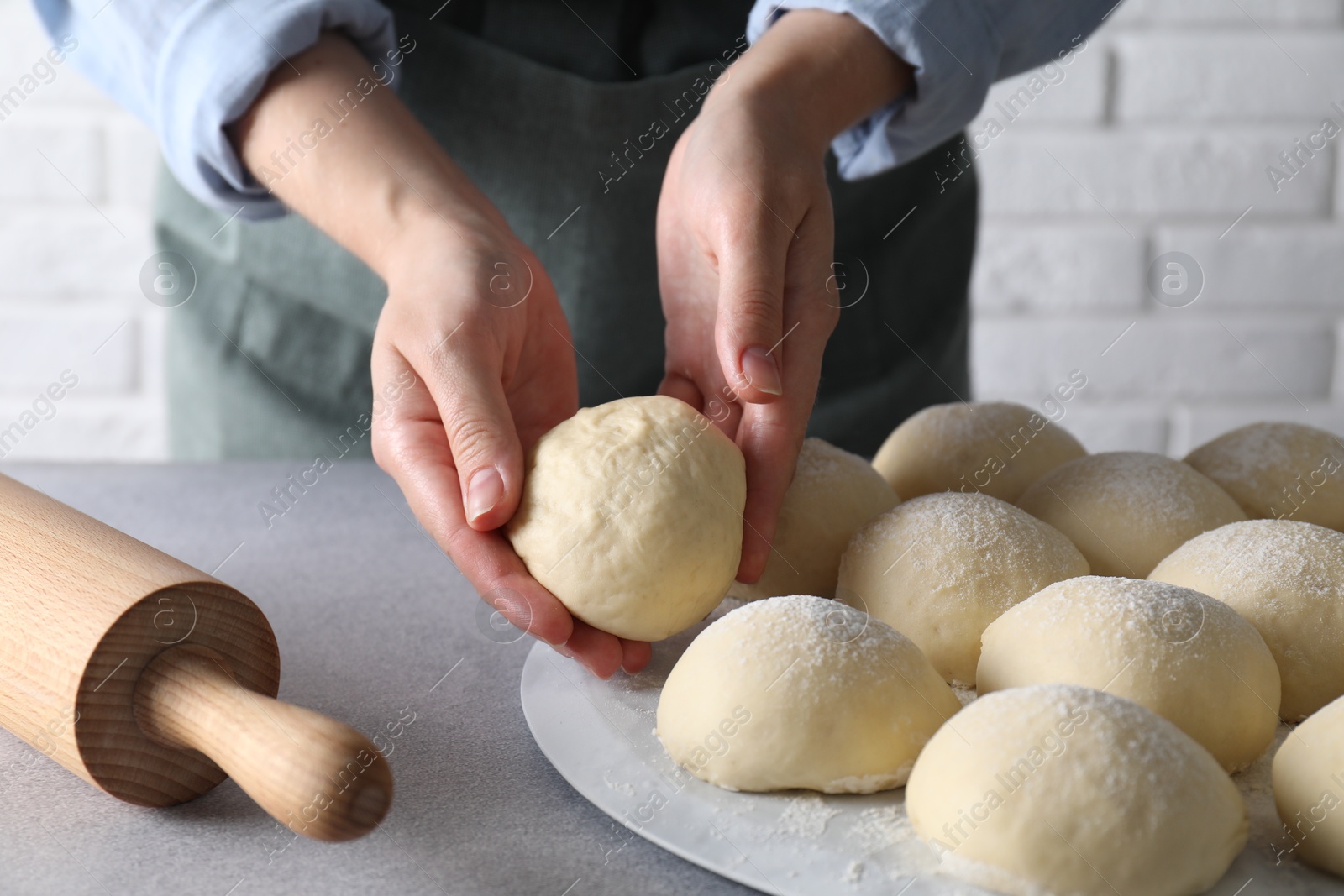 Photo of Woman making dough ball at grey table, closeup