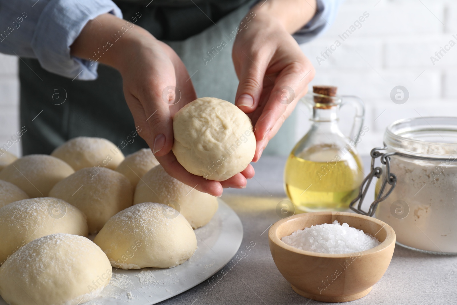 Photo of Woman making dough ball at grey table, closeup