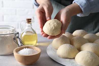 Photo of Woman making dough ball at grey table, closeup