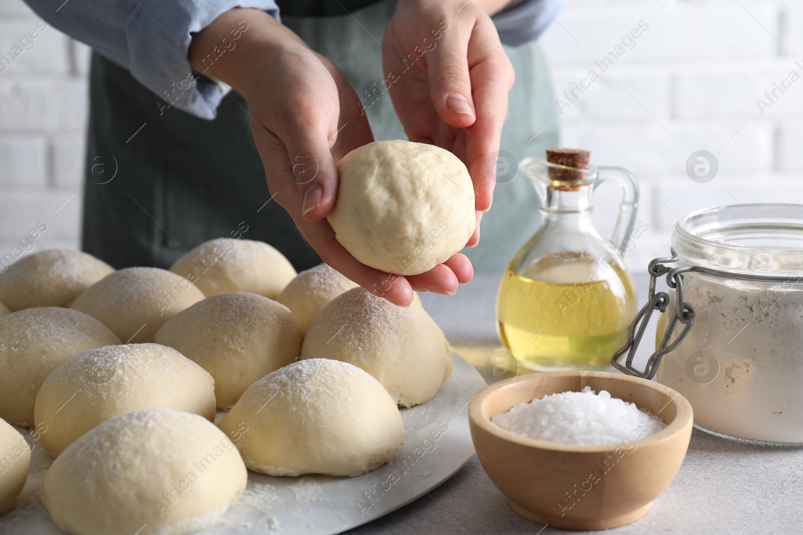 Photo of Woman making dough ball at grey table, closeup