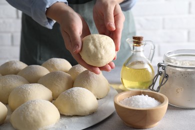 Photo of Woman making dough ball at grey table, closeup