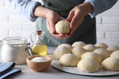 Woman making dough ball at grey table, closeup