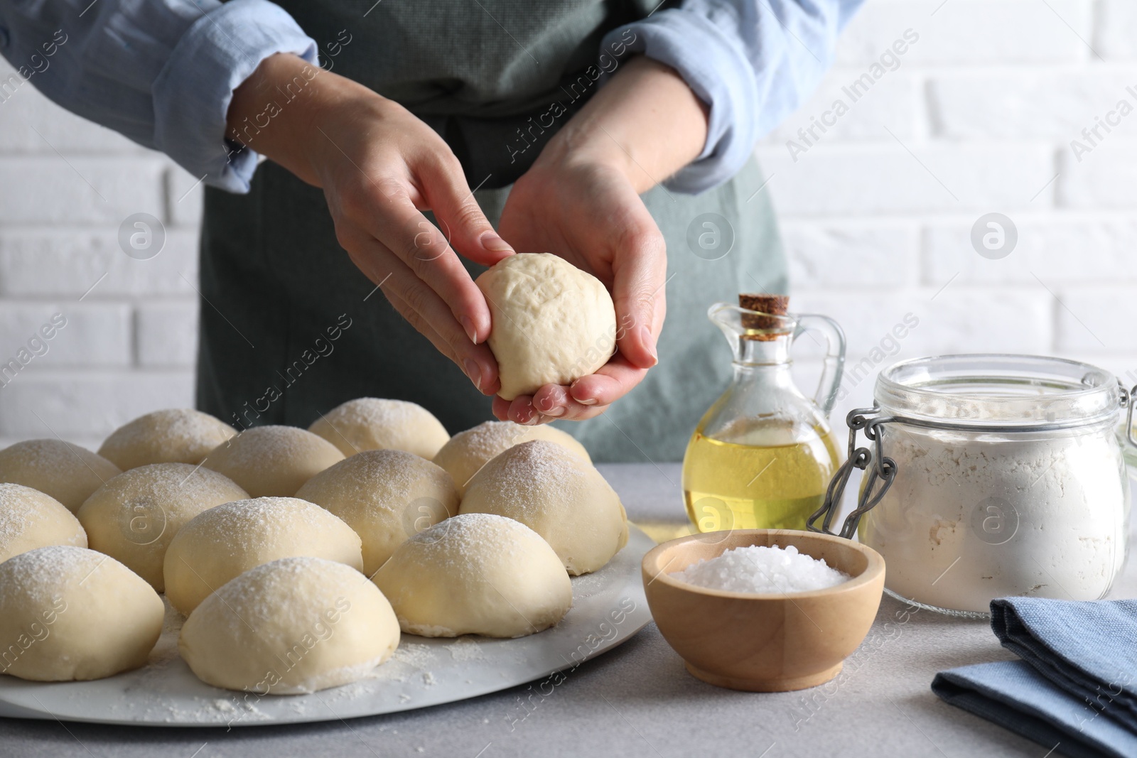 Photo of Woman making dough ball at grey table, closeup