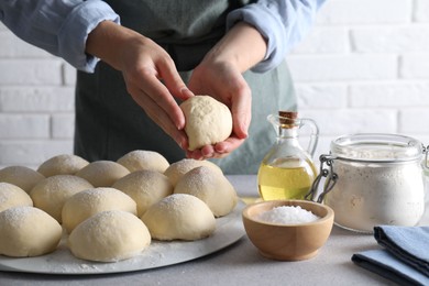 Woman making dough ball at grey table, closeup