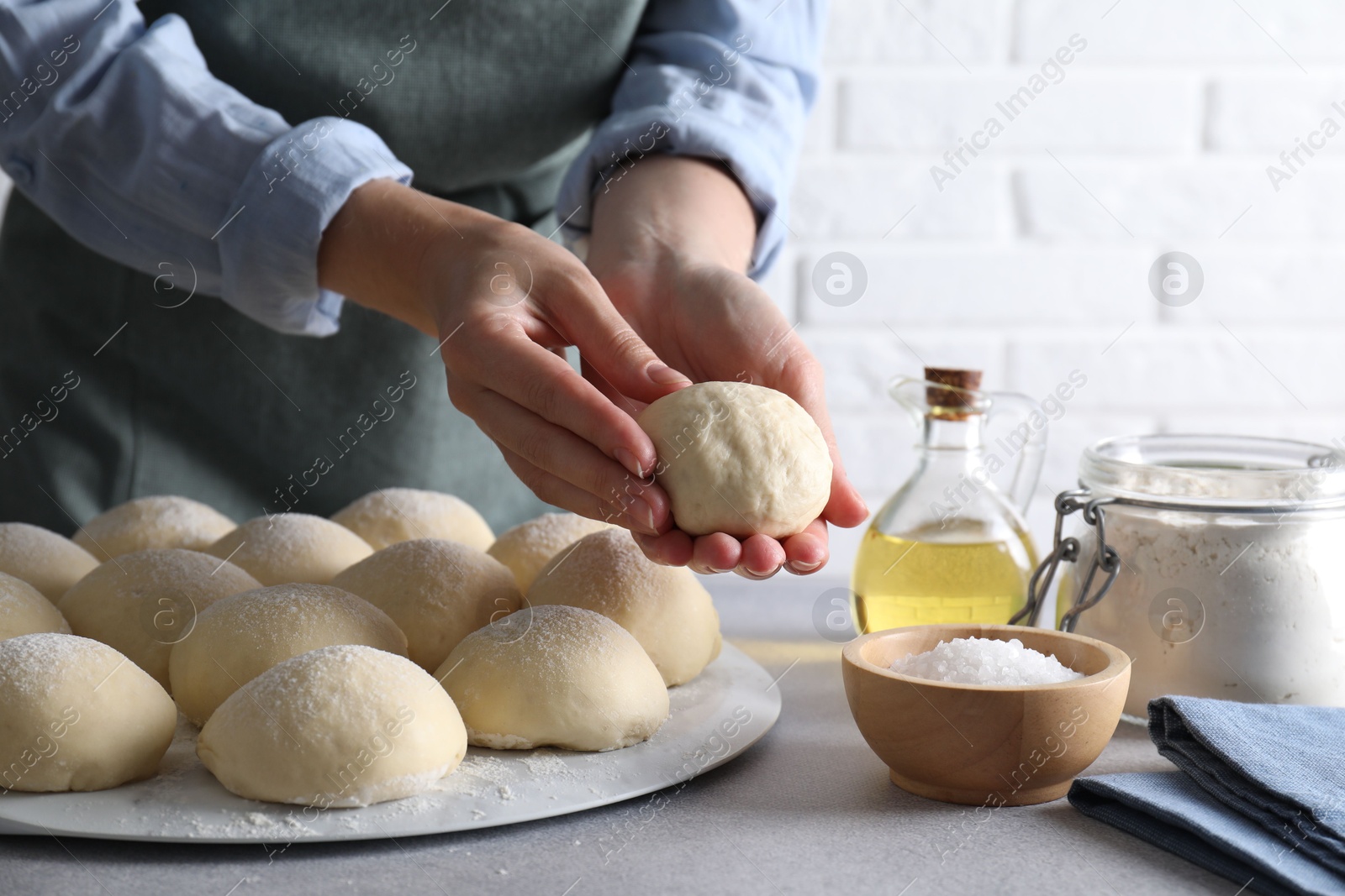 Photo of Woman making dough ball at grey table, closeup