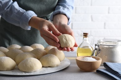 Woman making dough ball at grey table, closeup