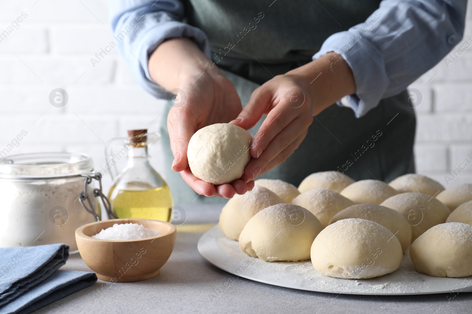 Photo of Woman making dough ball at grey table, closeup