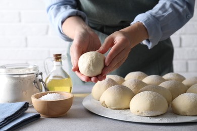 Woman making dough ball at grey table, closeup