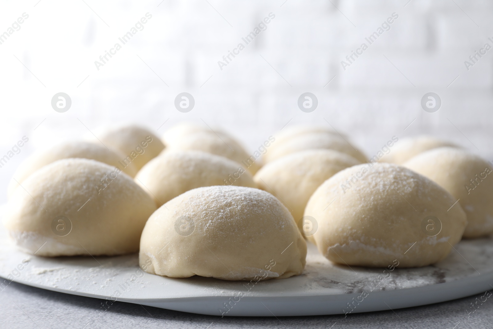 Photo of Raw dough balls on light grey table, closeup