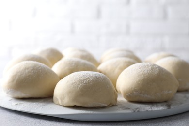 Photo of Raw dough balls on light grey table, closeup