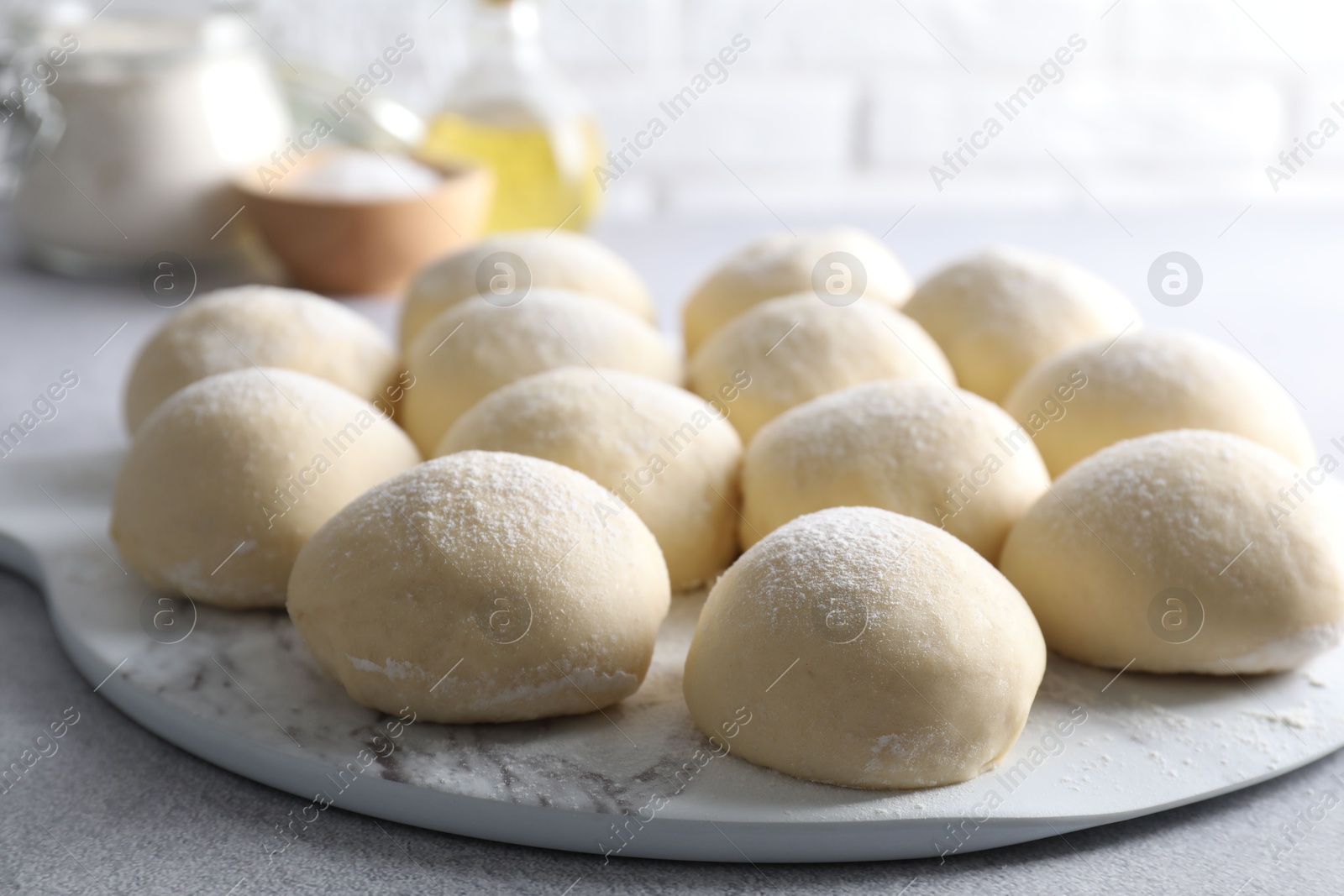 Photo of Raw dough balls on light grey table, closeup