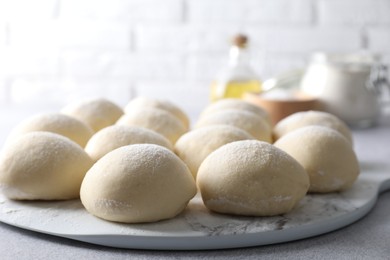 Photo of Raw dough balls on light grey table, closeup