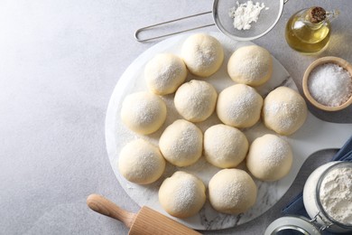 Raw dough balls, ingredients and rolling pin on light grey table, top view. Space for text