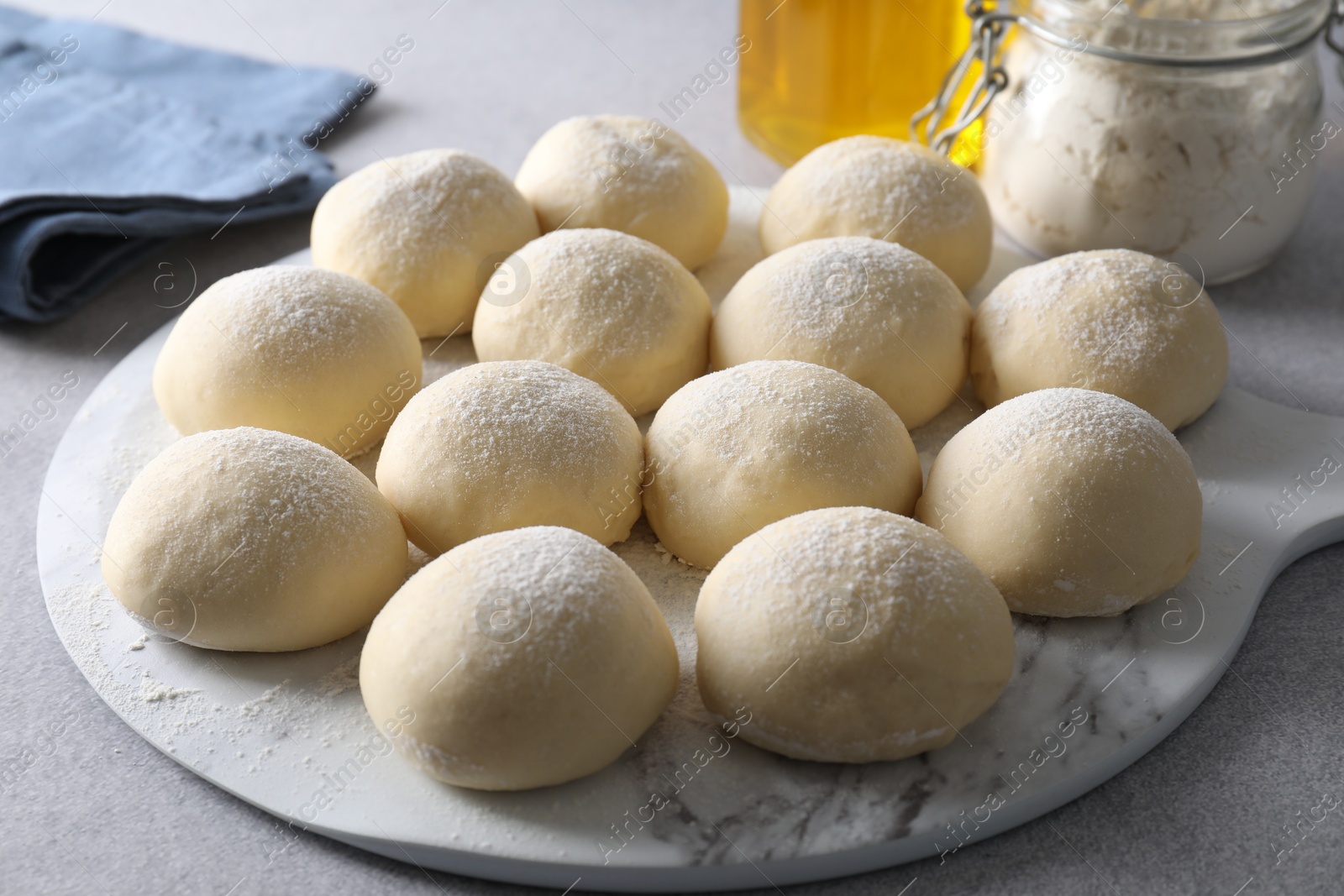 Photo of Raw dough balls and flour on light grey table