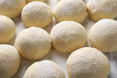 Photo of Many raw dough balls with flour on table