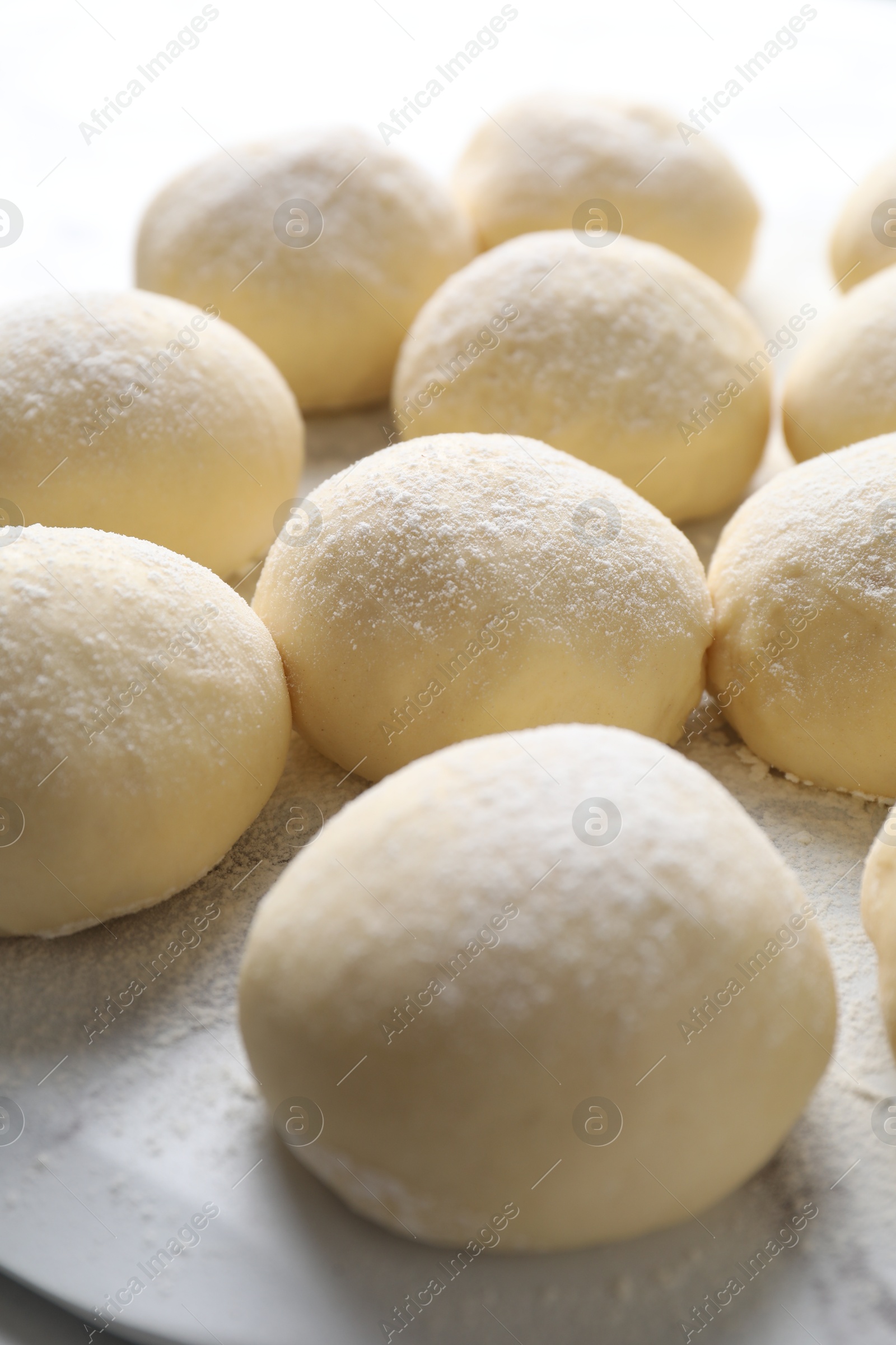 Photo of Many raw dough balls with flour on table