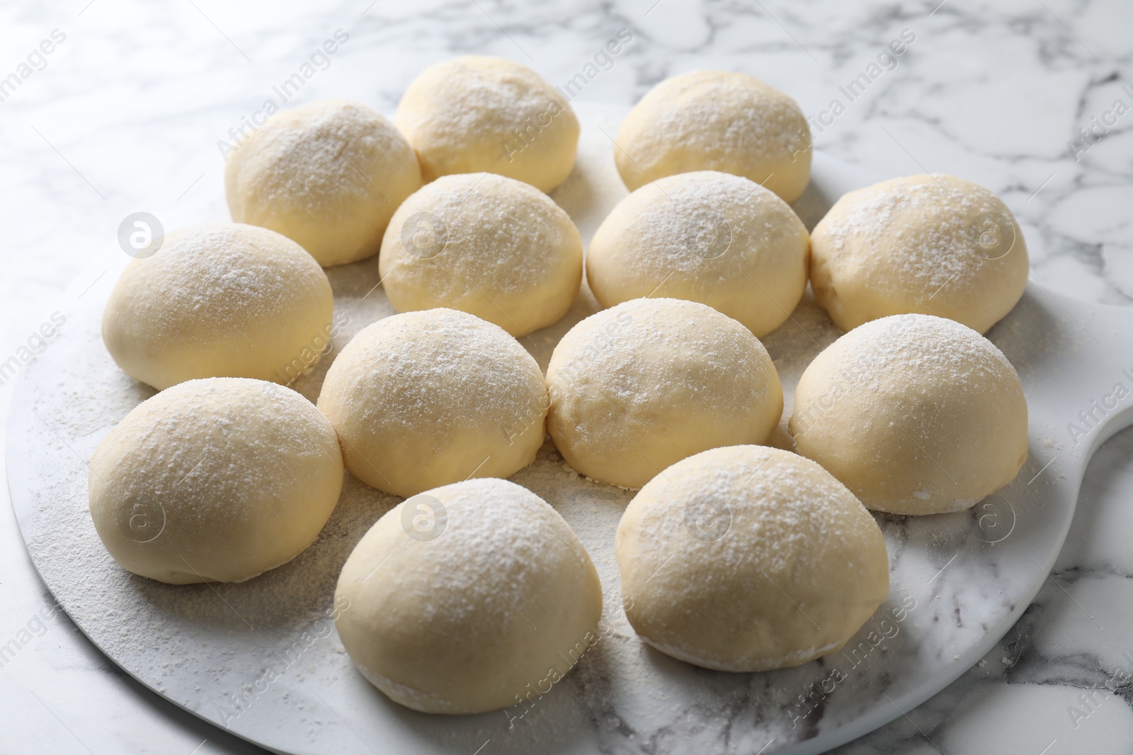 Photo of Raw dough balls on white marble table