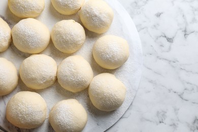 Photo of Raw dough balls on white marble table, top view. Space for text