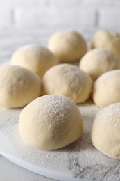 Photo of Many raw dough balls with flour on table