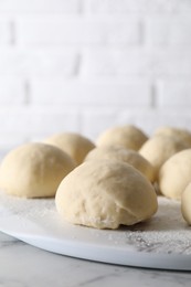 Photo of Raw dough balls on white marble table, closeup