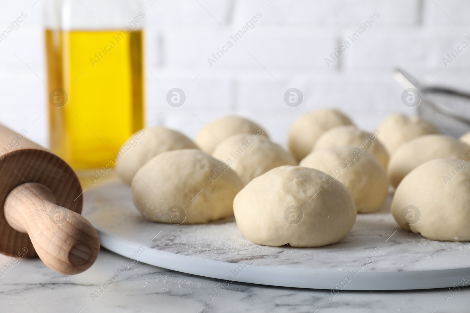 Photo of Raw dough balls and rolling pin on white marble table