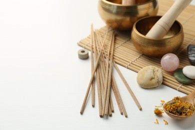 Photo of Incense sticks, Tibetan singing bowls, stones and dry flowers on white table, space for text