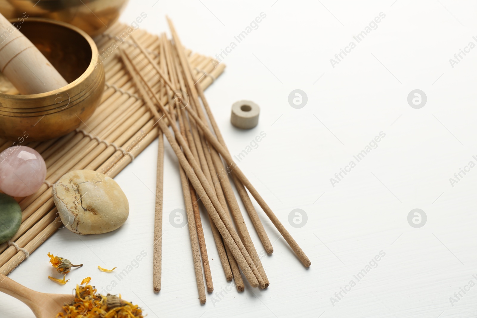 Photo of Incense sticks, Tibetan singing bowl, stones and dry flowers on white table, space for text