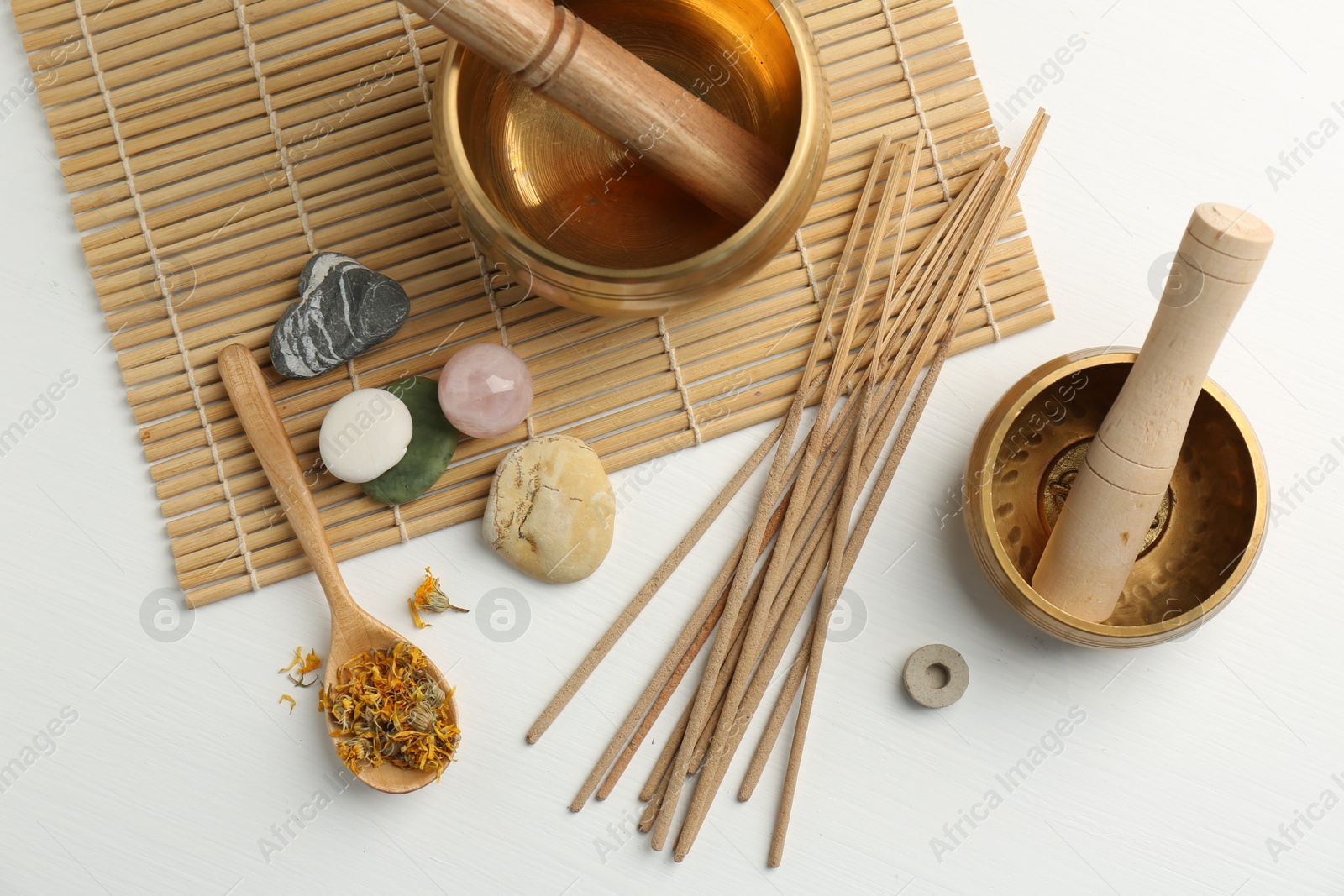 Photo of Incense sticks, Tibetan singing bowls, dry flowers and stones on white wooden table, top view