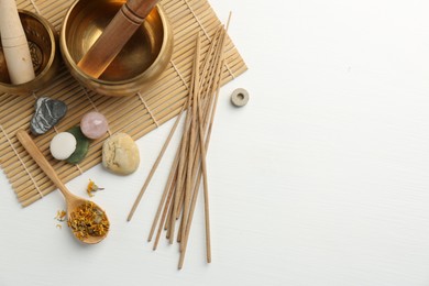 Incense sticks, Tibetan singing bowls, dry flowers and stones on white wooden table, top view. Space for text