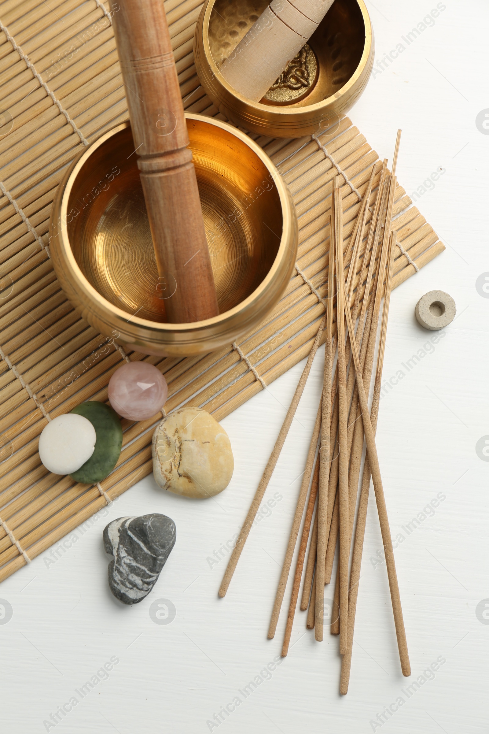 Photo of Incense sticks, Tibetan singing bowls and stones on white wooden table, top view