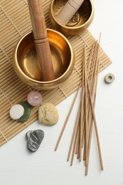 Incense sticks, Tibetan singing bowls and stones on white wooden table, top view