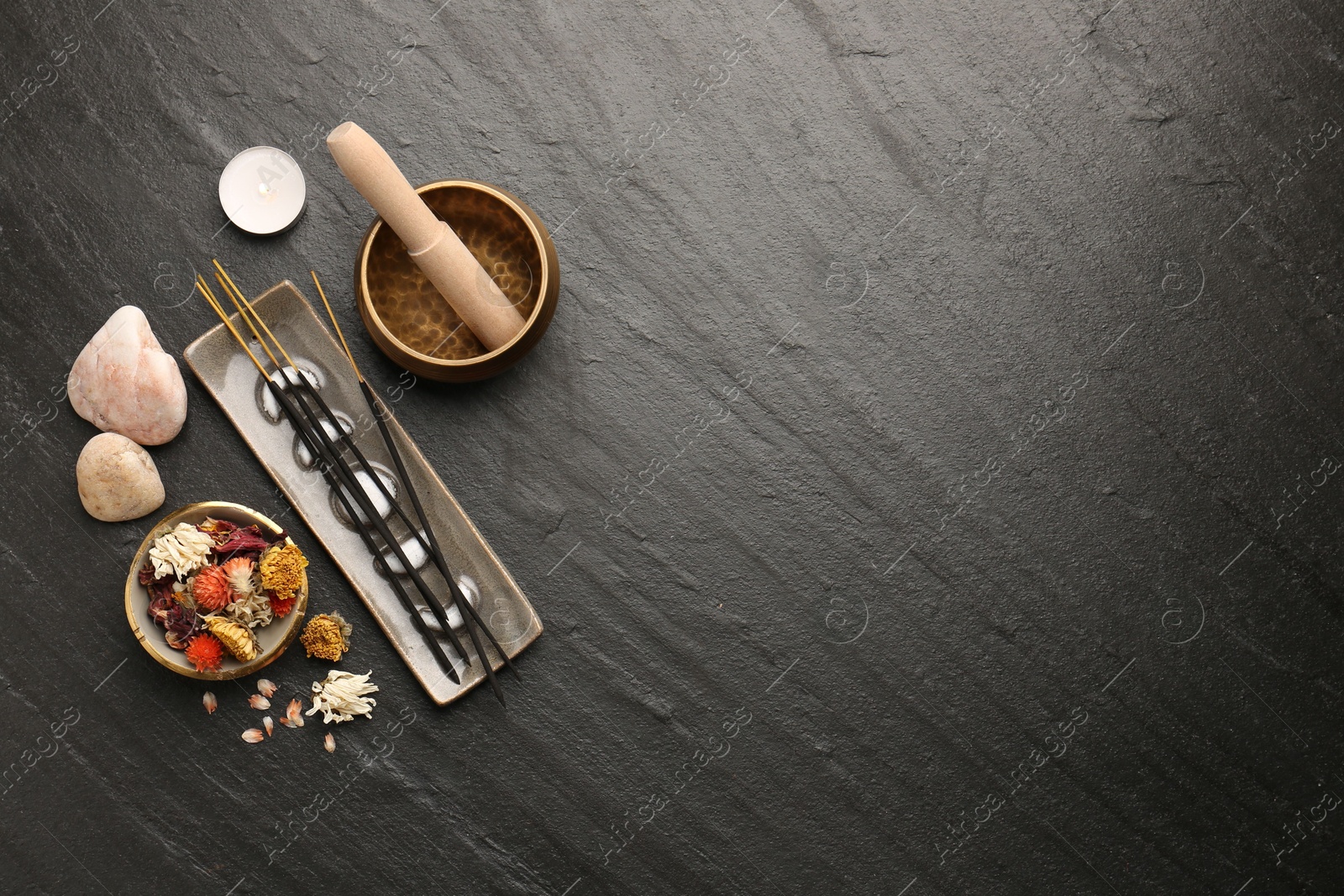 Photo of Incense sticks, Tibetan singing bowl, stones, dry flowers and candle on black table, flat lay. Space for text