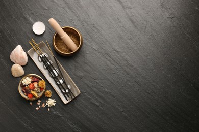 Photo of Incense sticks, Tibetan singing bowl, stones, dry flowers and candle on black table, flat lay. Space for text