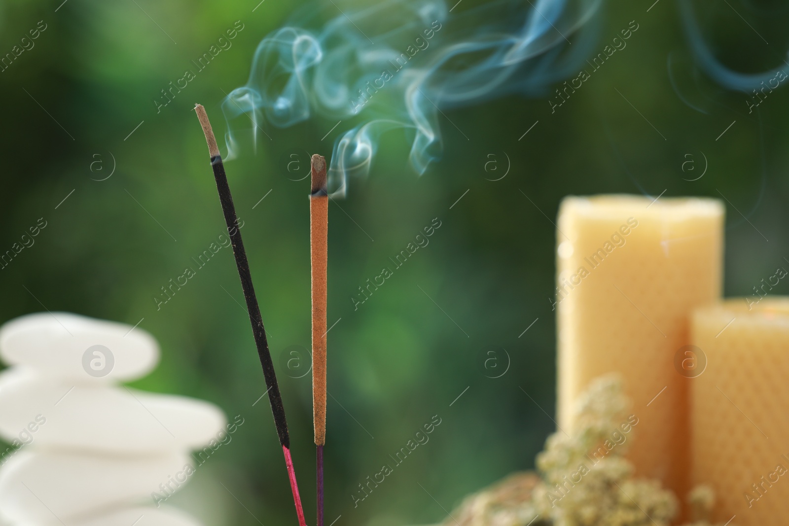 Photo of Two incense sticks smoldering against blurred background