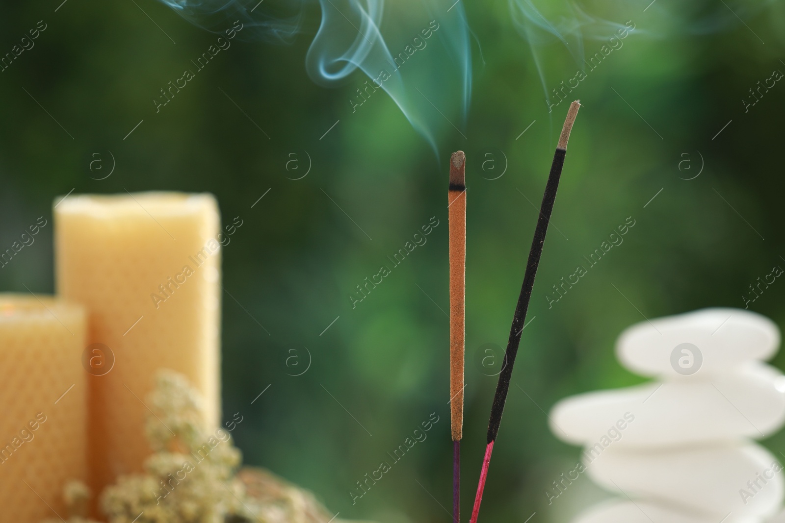 Photo of Two incense sticks smoldering against blurred background