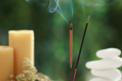 Photo of Two incense sticks smoldering against blurred background